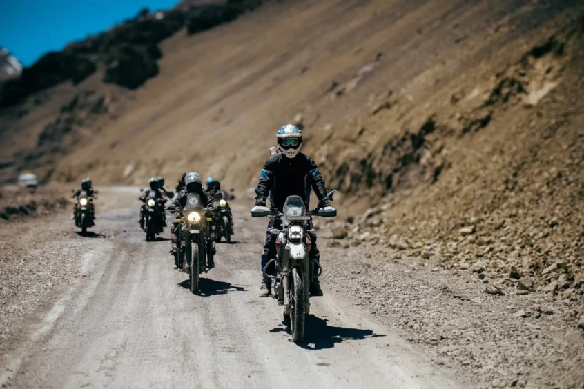 a group of people riding motorcycles on a dirt road
