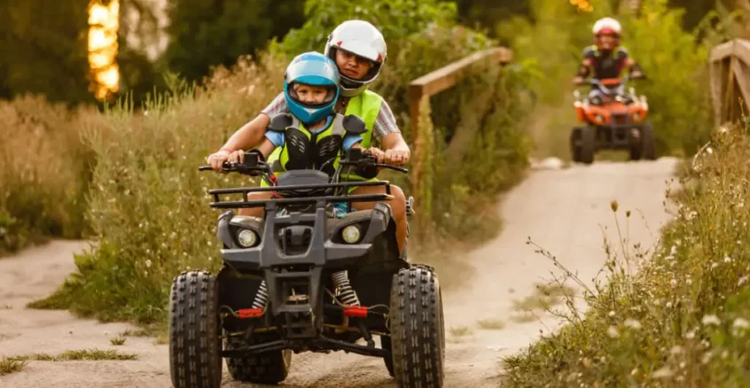 A man and child riding on an All-terrain vehicle.