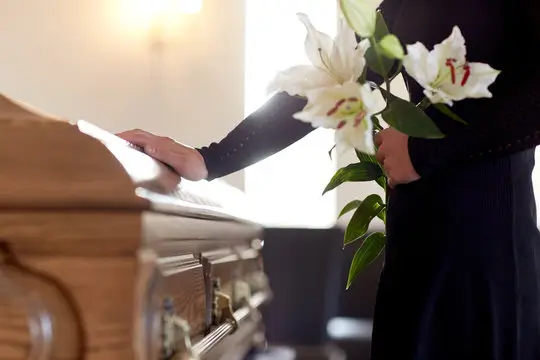 Man with lilies touches closed casket