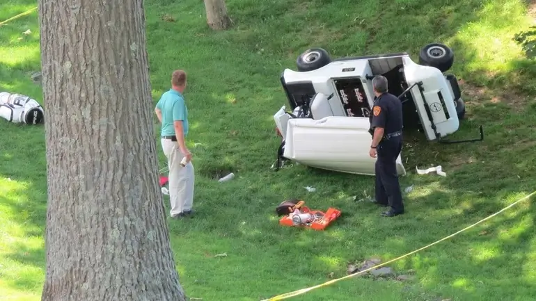 a man standing next to a golf cart that crashed into a tree